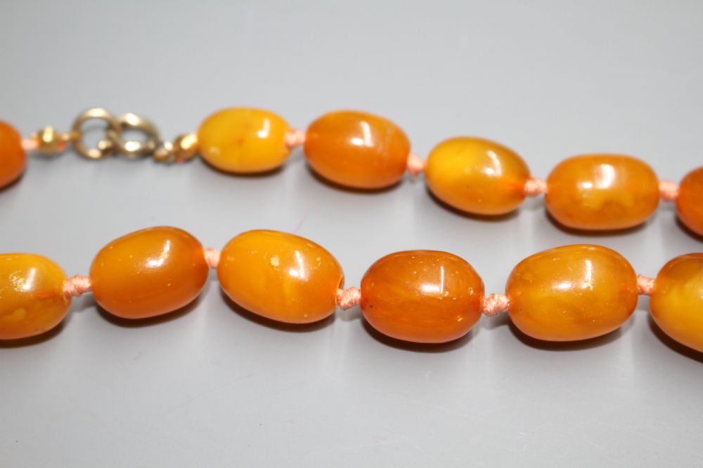 Two single strand graduated oval amber bead necklaces, with yellow metal clasps, one stamped 375,